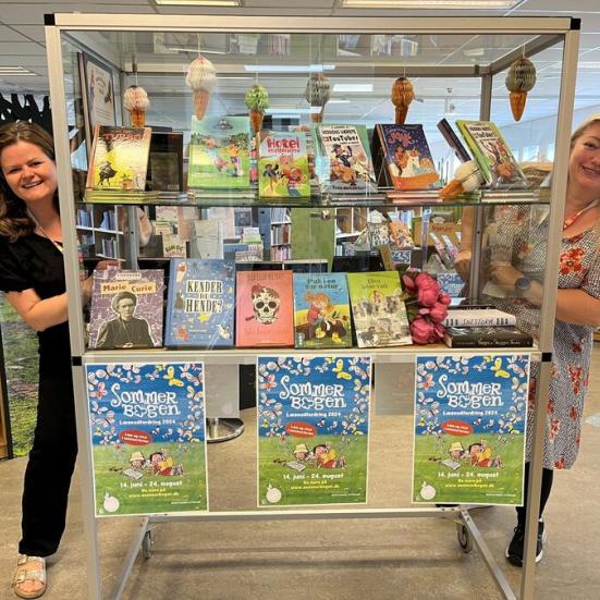 Anette og Tina står bag ved montre med bøger