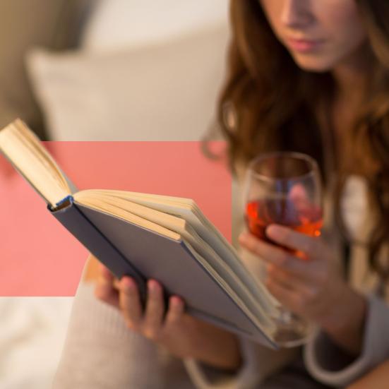 Kvinde læser en bog med et glas rødvin