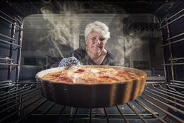 Kvinde tager en færdig bagt kage ud af ovnen