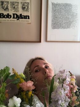 Marie Louise Tuxen omfavnet af en buket blomster på både sin høje og venstre side