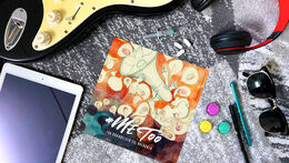 MeToo folder lægger i blandt en guitar, solbriller, høretelefoner og en tablet