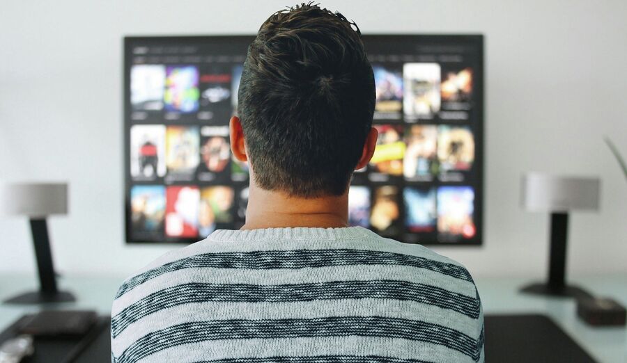 Mand ser tv med udvalg af film på skærmen