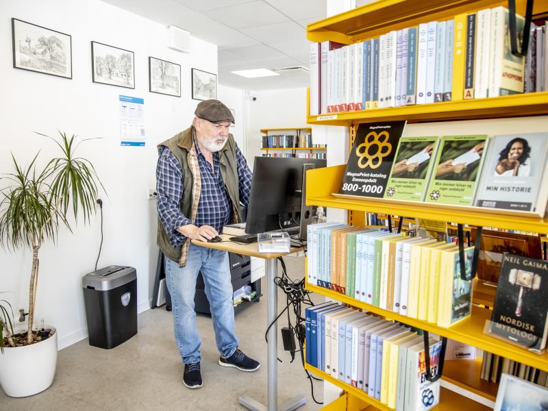 Mand står ved en pc på biblioteket