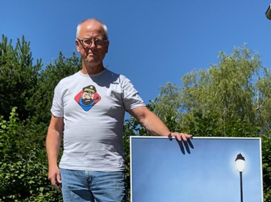 Erik Marquardtsen står udenfor med stor plakat med tintin